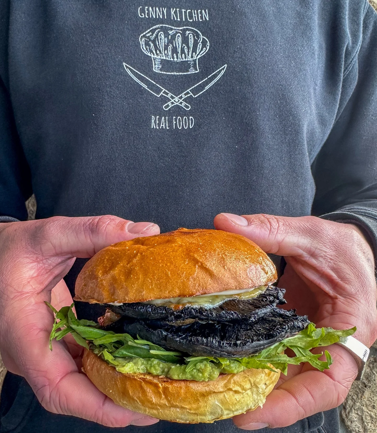 A Genny Kitchen mushroom burger with rocket and guacamole, held in a Real Food jumper